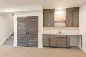 Kitchen with a sink, light colored carpet, light countertops, recessed lighting, and open shelves