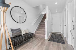 Foyer featuring recessed lighting, stairs, baseboards, and wood finished floors