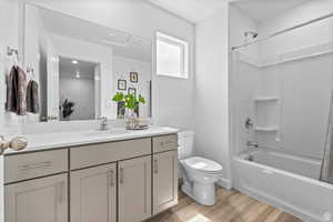 Bathroom with vanity, shower / bathing tub combination, toilet, and wood finished floors