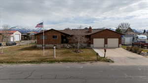 Ranch-style house featuring a front lawn, fence, a garage, and driveway