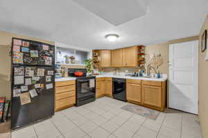 Kitchen with open shelves, black appliances, light countertops, and a sink