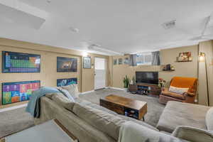 Living room featuring concrete block wall, carpet, visible vents, and baseboards