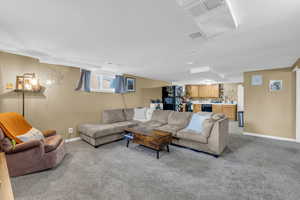Living area featuring visible vents, bar, light colored carpet, and baseboards