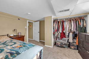 Bedroom featuring visible vents, carpet flooring, a closet, and concrete block wall