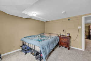 Carpeted bedroom featuring a textured ceiling, concrete block wall, and baseboards