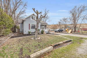 Bungalow-style house with a shingled roof, a front lawn, and a playground