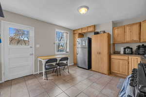 Kitchen featuring light tile patterned floors, stone countertops, freestanding refrigerator, and baseboards