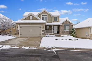 View of front of home with concrete driveway, an attached garage, and stone siding