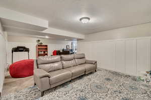 Carpeted living room with a decorative wall, wainscoting,