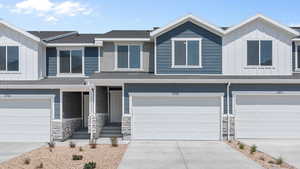 View of front of house featuring driveway, a garage, board and batten siding, and stone siding
