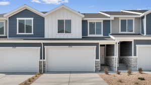 Multi unit property with concrete driveway, a garage, board and batten siding, and stone siding