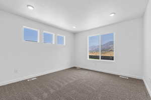 Unfurnished room with visible vents, plenty of natural light, baseboards, and dark carpet
