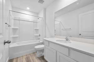 Bathroom featuring vanity, wood finished floors, visible vents, tub / shower combination, and toilet