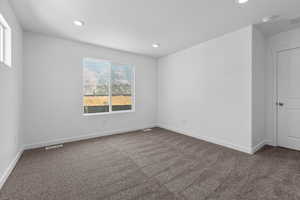 Carpeted spare room featuring visible vents, recessed lighting, and baseboards