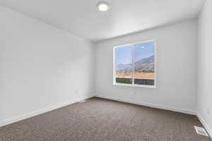 Carpeted empty room with visible vents and baseboards