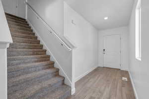 Stairs featuring visible vents, recessed lighting, baseboards, and wood finished floors