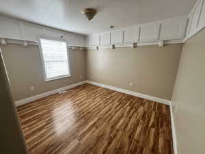 Unfurnished room with wood finished floors and a textured ceiling