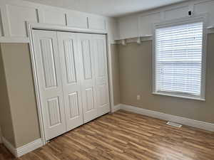 Unfurnished bedroom featuring a closet, wood finished floors, and a textured ceiling