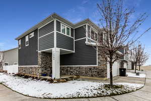 Snow covered property featuring fence and stone siding
