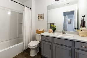 Bathroom with vanity, wood finished floors, visible vents, toilet, and shower / tub combo with curtain