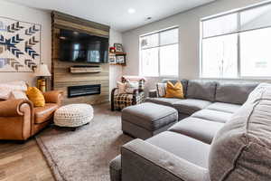 Living area with recessed lighting, visible vents, wood finished floors, and a fireplace
