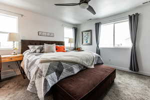 Carpeted bedroom with a ceiling fan, baseboards, visible vents, and a textured ceiling