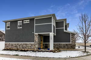 View of front of home featuring stone siding and fence
