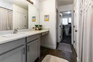 Full bath with vanity, wood finished floors, and baseboards