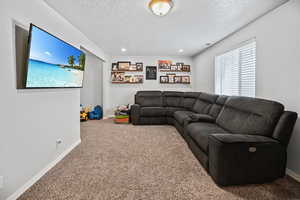 Living area featuring baseboards, carpet floors, and a textured ceiling