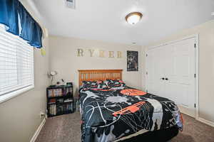 Bedroom featuring a closet, carpet floors, a textured ceiling, baseboards, and visible vents