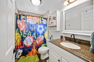 Bathroom with a textured ceiling, a shower with shower curtain, toilet, vanity, and tile patterned flooring