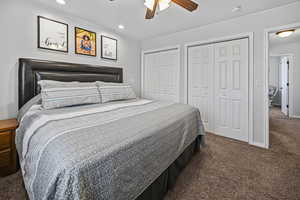 Carpeted bedroom with two closets, a ceiling fan, baseboards, and recessed lighting