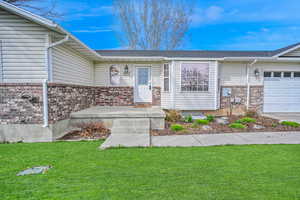 Property entrance with a lawn, brick siding, and a garage
