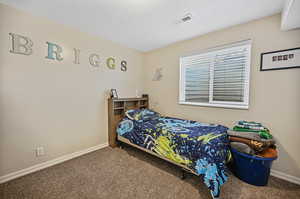 Carpeted bedroom with baseboards, visible vents, and a textured ceiling