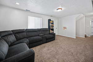 Living room featuring carpet flooring, a textured ceiling, baseboards, and visible vents
