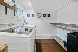 Laundry room featuring a wainscoted wall, washing machine and clothes dryer, and laundry area
