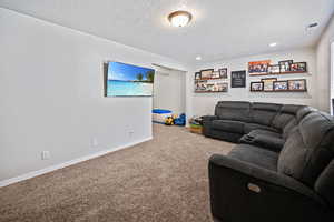 Living area with a textured ceiling, visible vents, baseboards, recessed lighting, and carpet floors