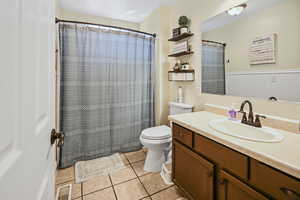 Bathroom with a shower with curtain, tile patterned flooring, vanity, toilet, and visible vents