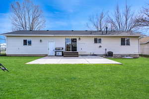 Rear view of house featuring a yard, central air condition unit, and a patio area