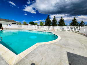Community pool featuring a patio and fence