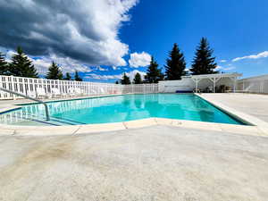 Pool with a patio and fence