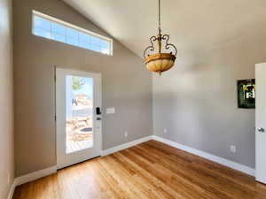 Foyer with lofted ceiling, wood finished floors, and baseboards