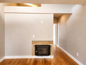 Interior space with a fireplace, a textured ceiling, baseboards, and wood finished floors