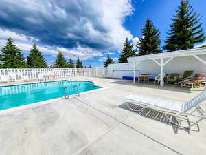 View of swimming pool with a fenced in pool, fence, and a patio area