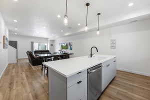 Kitchen with visible vents, a sink, open floor plan, light wood-type flooring, and stainless steel dishwasher