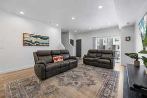 Living room featuring recessed lighting, a textured ceiling, light wood-type flooring, and baseboards