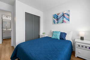 Bedroom with a closet, connected bathroom, and light wood finished floors