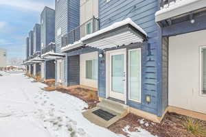 Snow covered property entrance featuring a balcony