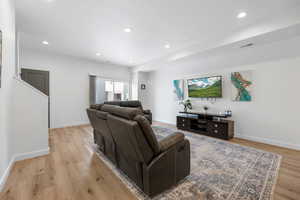 Living area with recessed lighting, visible vents, light wood-style flooring, and baseboards