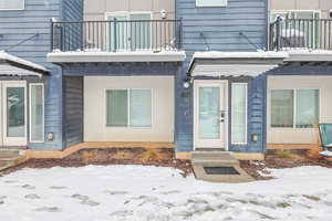 Snow covered property entrance with a balcony